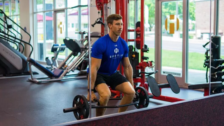 A Strong Young Man in Blue Shirt Lifting Weights at HiTONE Fitness Gym