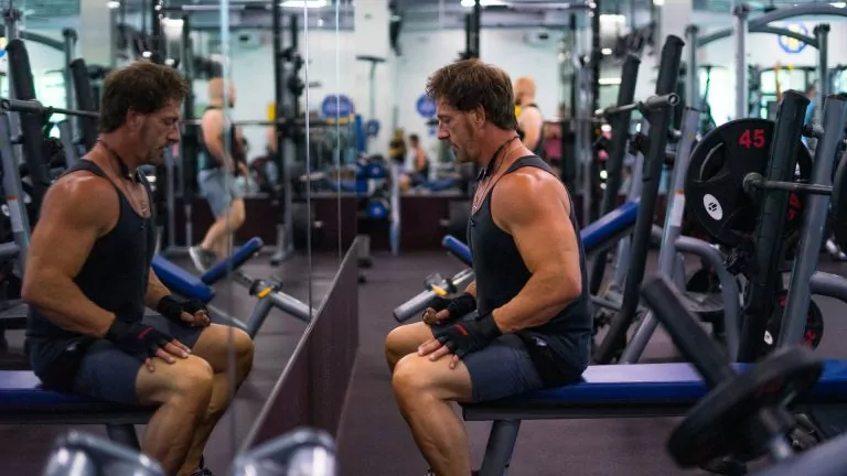 Man Sitting on The Bench In Front Of a Mirror at HiTONE Fitness Facility