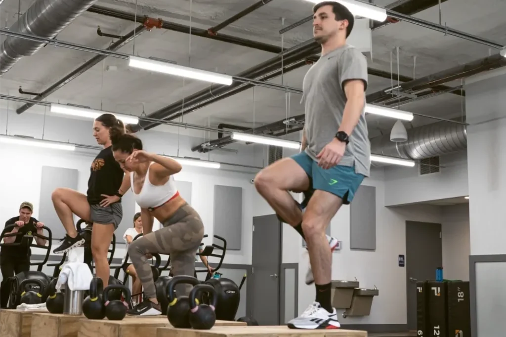 Multiple people doing calisthenics in a gym.