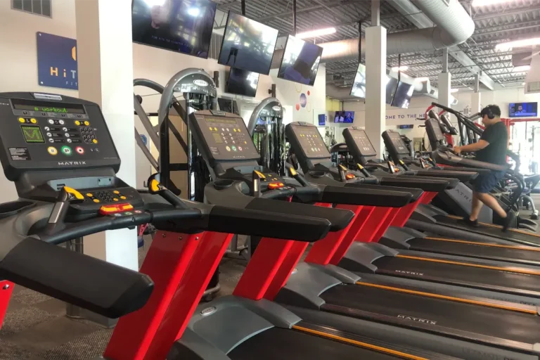 Six treadmills at a gym. A man in shorts exercises on one of them.