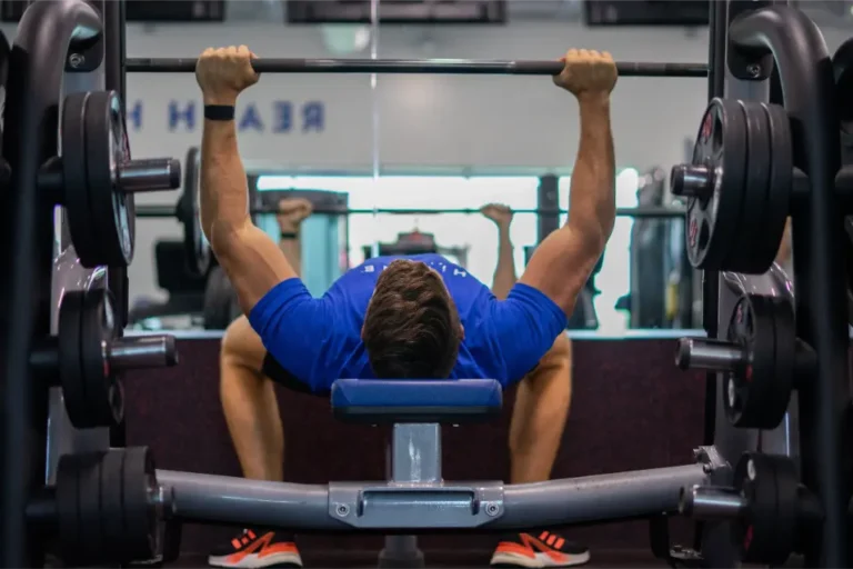 Man doing a bench press exercise on a smith machine.