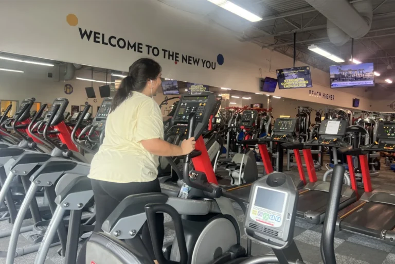 A woman running on an elliptical cross trainer at a gym.