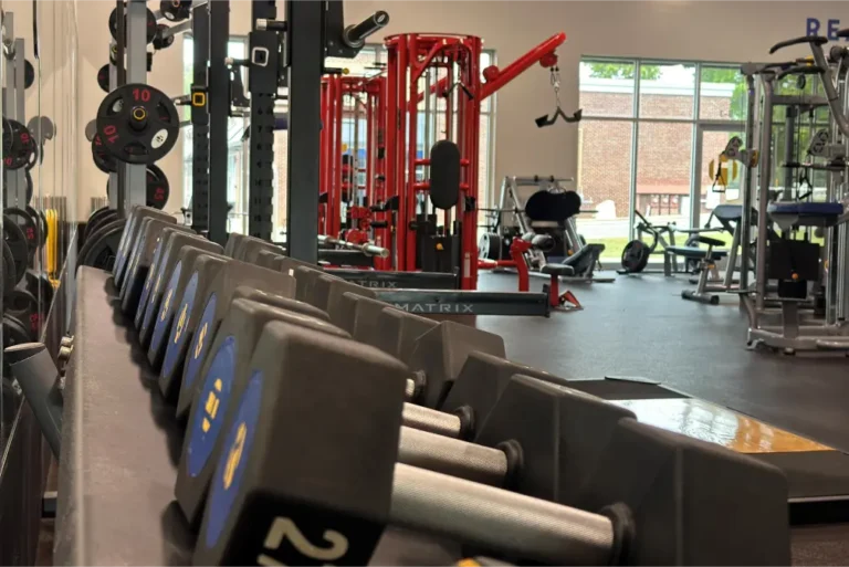 Inside of a gym seen from a hexagonal dumbbell rack.