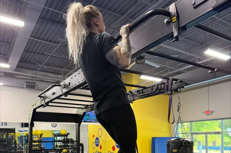 Woman performing pull-up in modern gym.