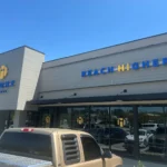 A store with the signs "HiTONE Fitness" and "REACH HIGHER" in blue lettering. A truck is parked in front.