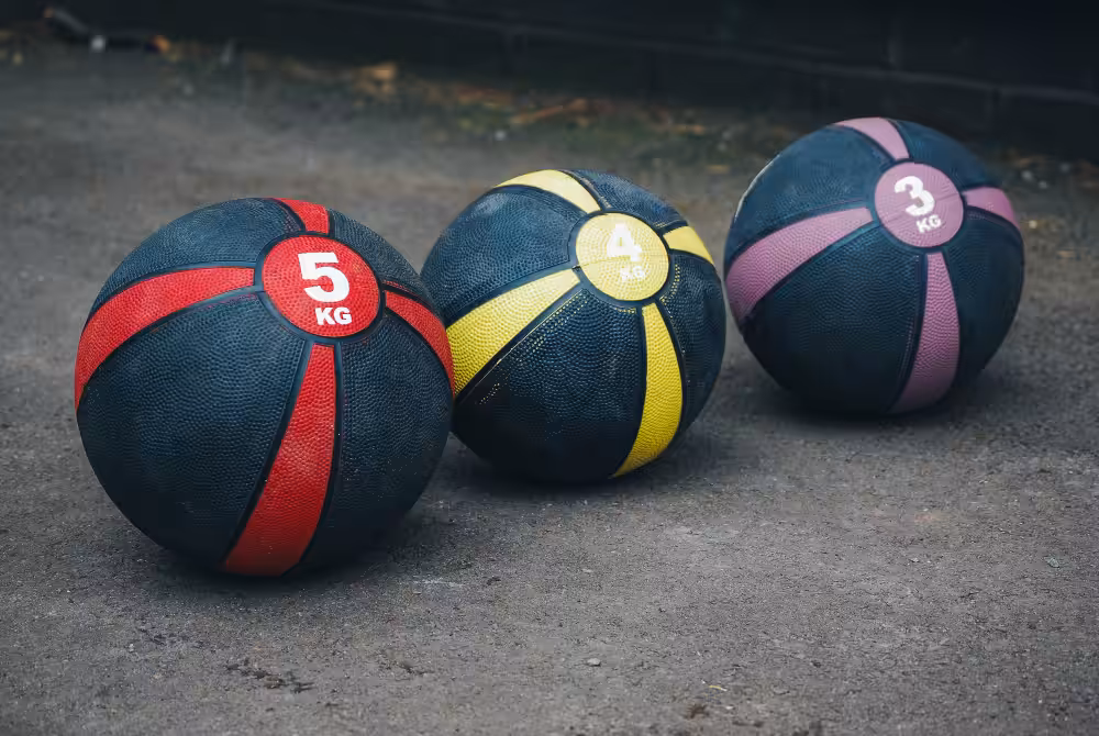 Three weighted medicine balls on concrete surface.
