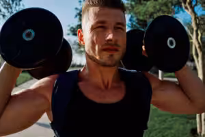 Man lifting weights outdoors, focusing on exercise.