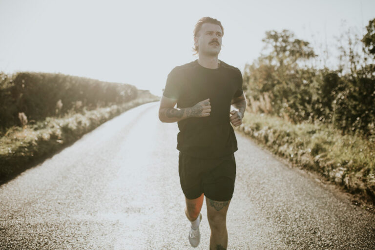 Man running on sunny rural road.