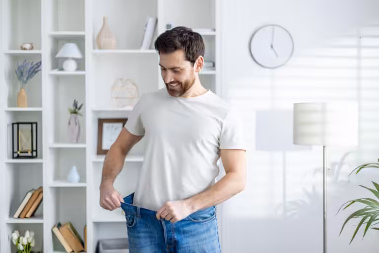 Man wearing loose jeans, smiling at home.