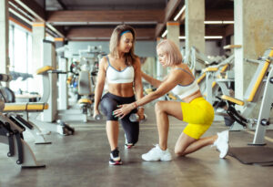 Personal trainer guiding woman in gym workout.