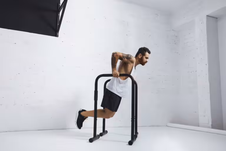 Man performing dips on parallel bars indoors