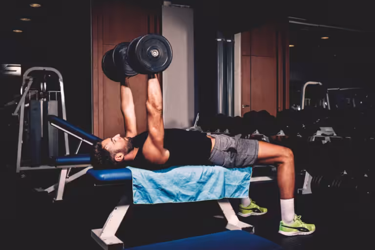 Man lifting dumbbells on gym bench