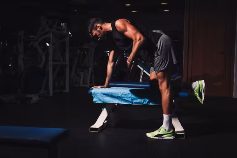 Man performing dumbbell row on bench in gym