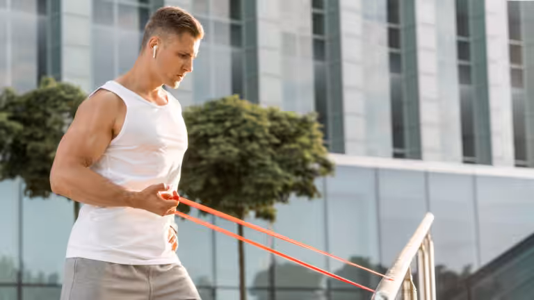 Man exercising with resistance band outdoors near building