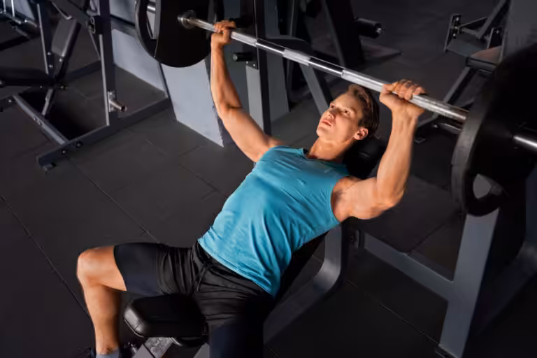 Man performing incline barbell bench press at gym