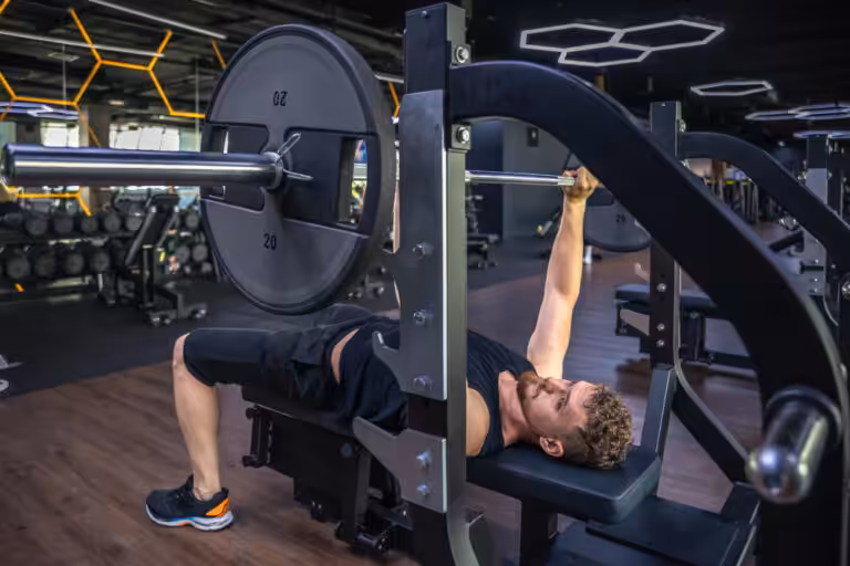 Man bench pressing barbell in modern gym