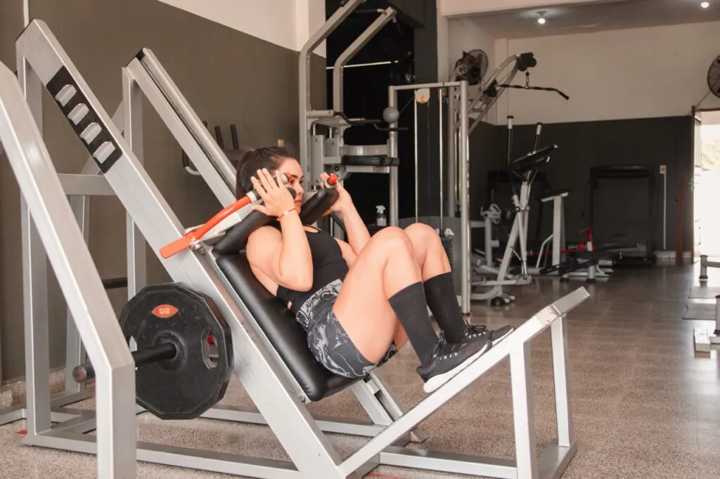 Woman using leg press machine at gym