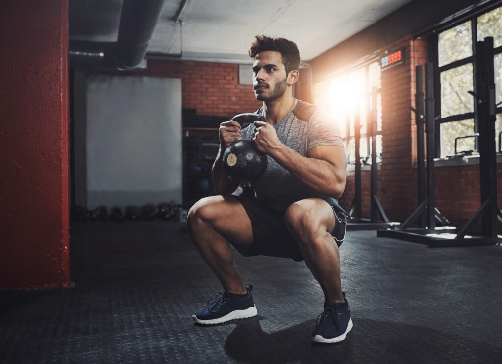 Man performing kettlebell goblet squat in gym